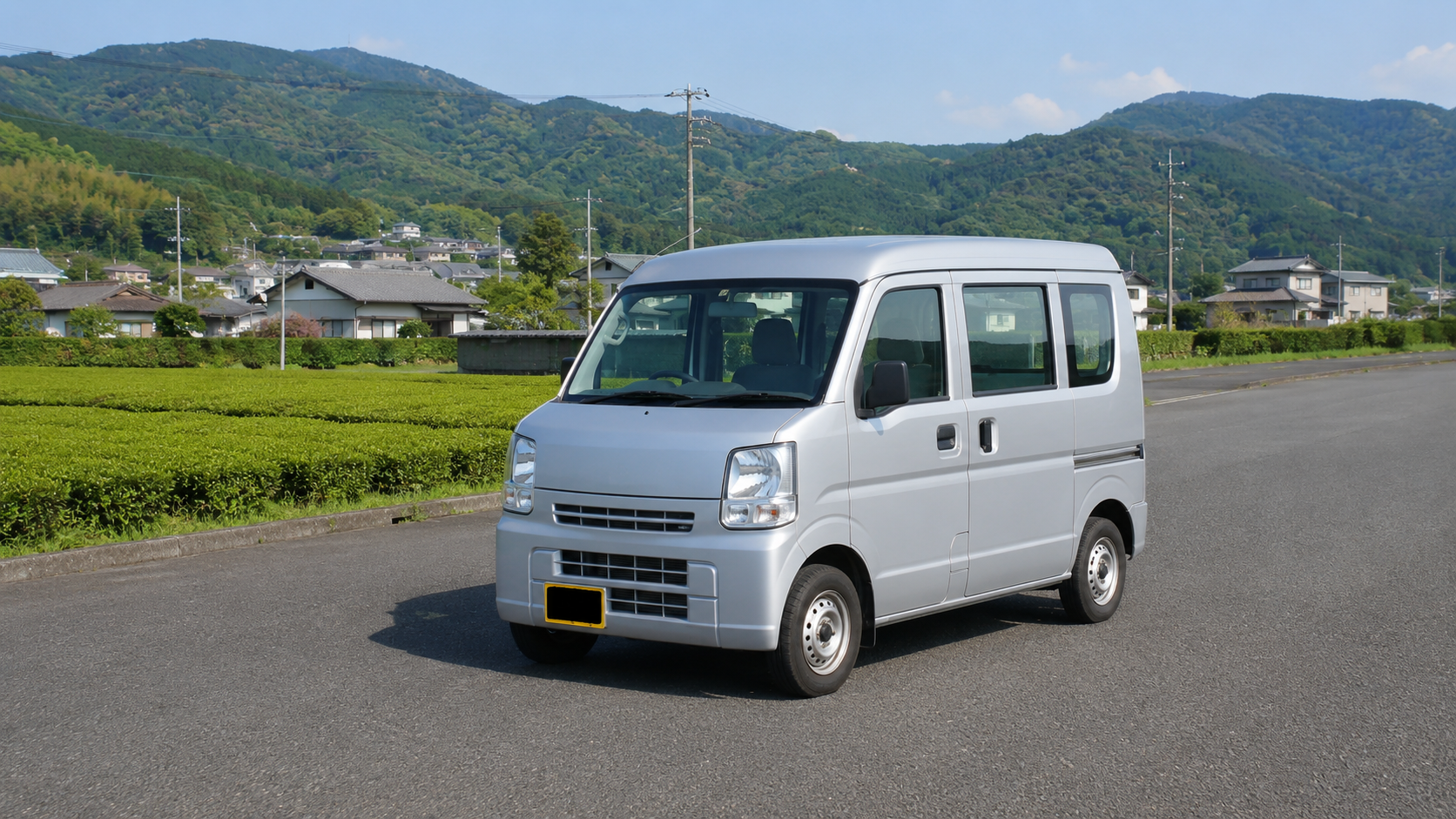 地域道路沿いに停車するシルバーの軽貨物車両の写真